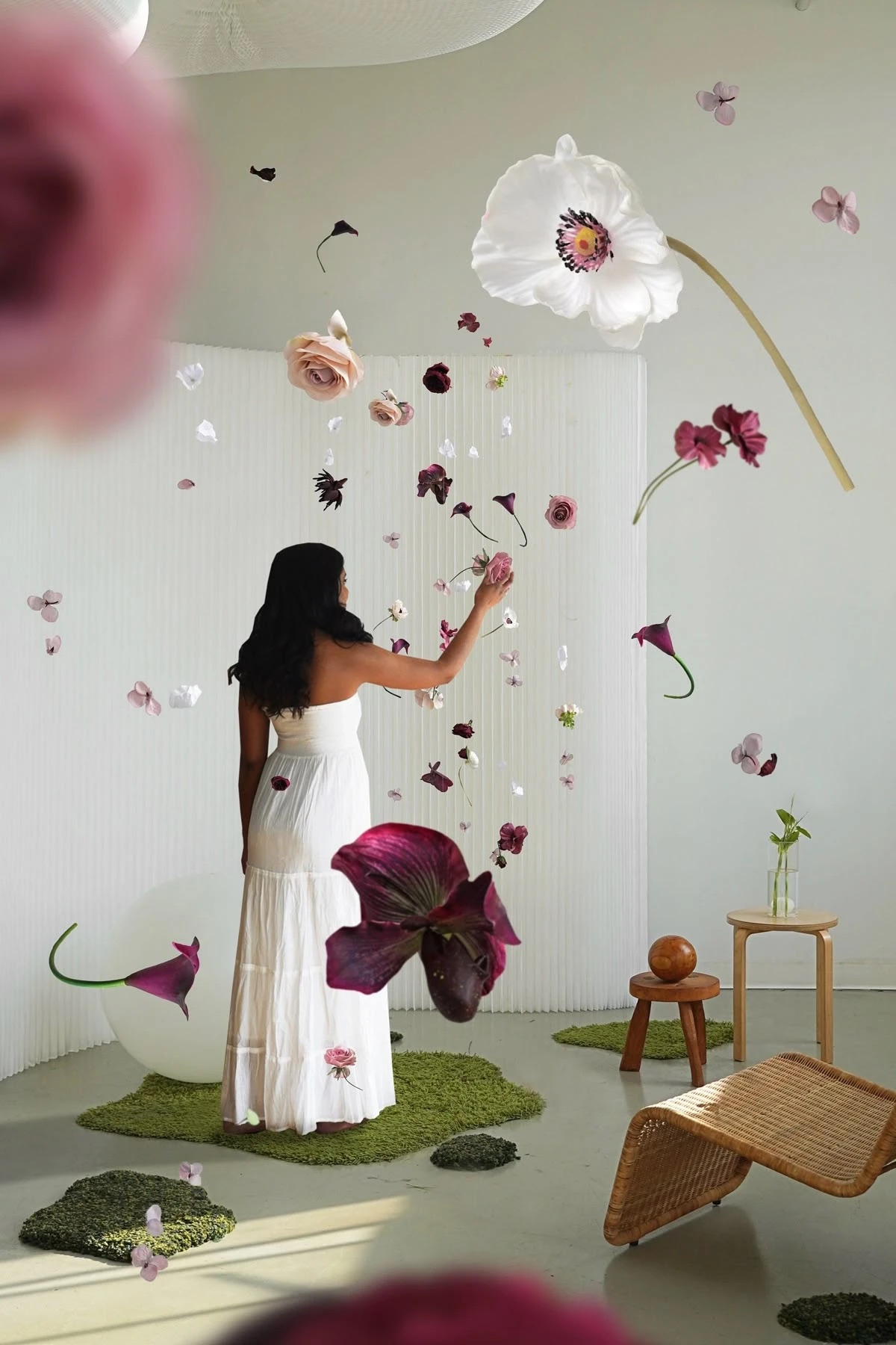 Flowers in burgundy, blush and white hanging at different heights in a white room, with one giant white poppy