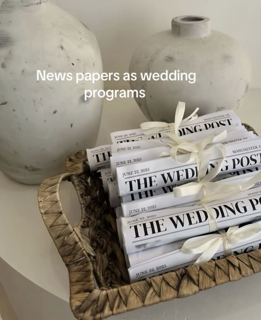 Rolled wedding newspapers tied with cream ribbon in a woven basket