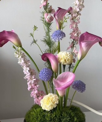 Calla lilies, delphinium and carnations rising from a moss base