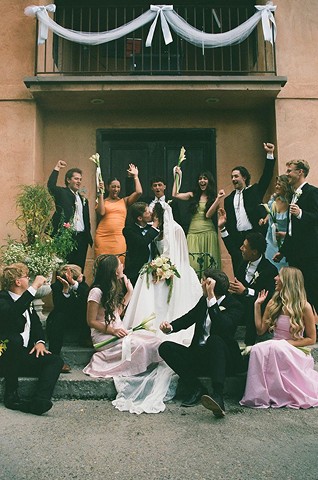 Whole wedding party cheering on the front steps