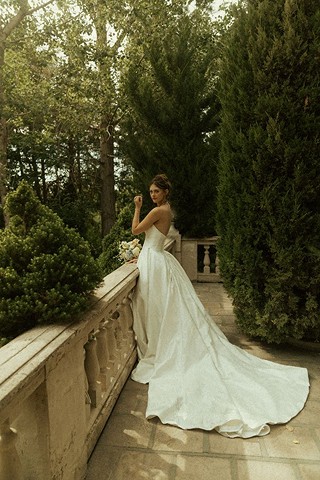 Bride on a stone balcony surrounded by greenery