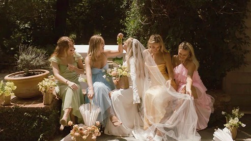 Bride and bridesmaids in mismatched pastels in a garden