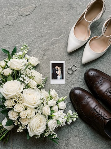 White roses, shoes, rings and a polaroid on stone