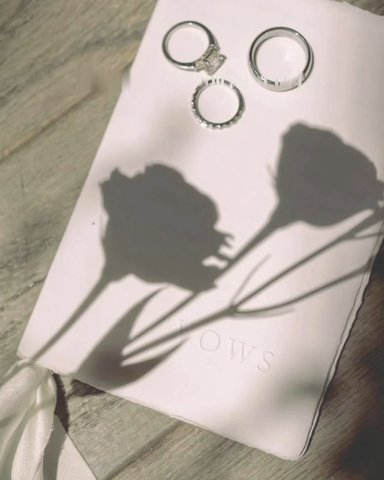Rings on the vows booklet with a floral shadow