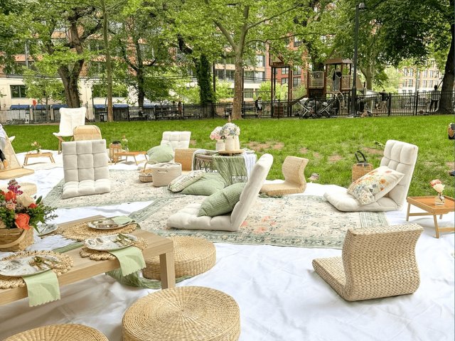 Floor cushions, woven poufs and low tables set up on a garden lawn